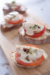 Sandwiches with butter, tomato, chicken and mayonnaise on wooden board as background