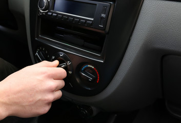 Man adjusting air conditioner system in modern car, closeup