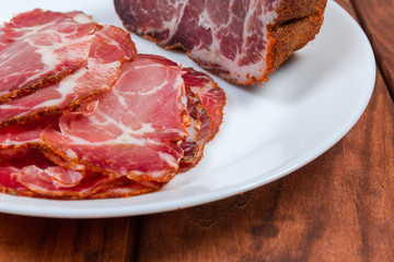 Partly sliced dried pork neck on dish close-up