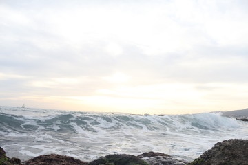 Sunset on the background of the sea and reefs with a small ship in the distance on island Palma de Mallorca in Spain