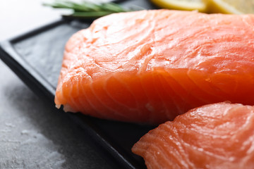 Plate with cut salmon fillet on table, closeup