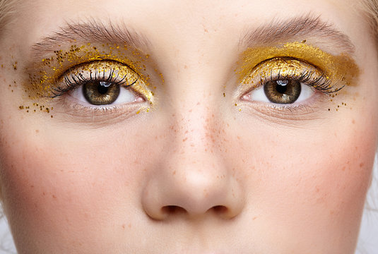 Closeup macro shot of human female eye with yellow smoky eyes beauty makeup.