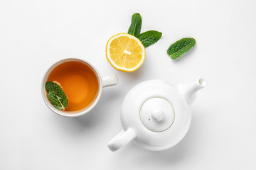 Teapot, cup of hot beverage, lemon and mint on white background