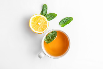 Cup of hot tea, mint and lemon on white background