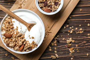 Bowl with tasty yogurt, oatmeal and almonds on wooden background
