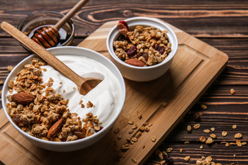 Bowl with tasty yogurt, oatmeal and almonds on wooden background