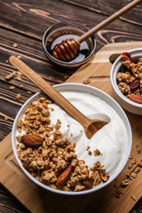 Bowl with tasty yogurt, oatmeal and almonds on wooden background