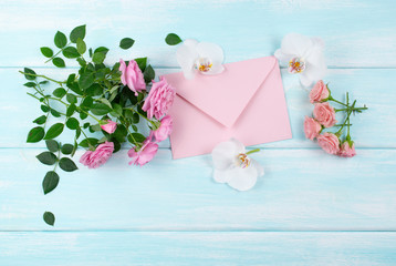 Roses and orchids flowers and envelope on wooden background