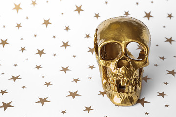 Golden human skull on white background with stars