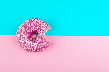 Pink glazed donut on color background. Flat lay.