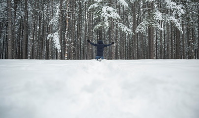 man with outstretched hands in a pine forest in winter