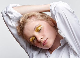 Portrait of a young blonde woman with closed eyes on gray background