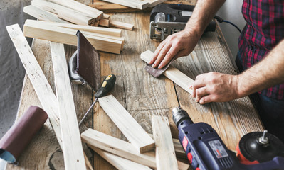 Carpenter working carpentry workshop Man sanding manually plank - obrazy, fototapety, plakaty
