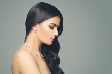 Glamorous woman with makeup, long hair curly hair, diamond necklace and earrings. Fashion jewelry...