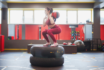 Sportswoman squatting with bag on tyres
