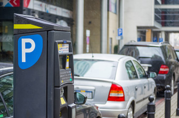 Parking meter machine on the street. Ticket pay station with cars on the parking places at the background.