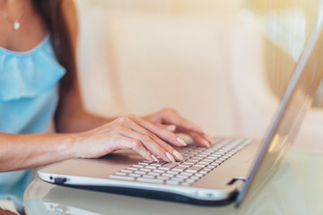 Close-up shot of female hands typing on laptop keyboard