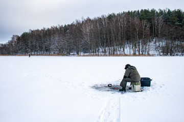 Fototapeta na wymiar Fishing on a frozen lake in winter with sonar