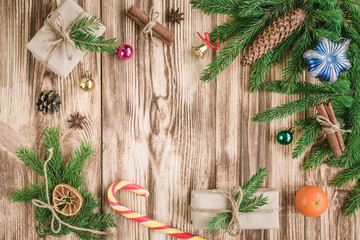 Fototapeta na wymiar Christmas composition of fir branches with Christmas sticks, cones, cinnamon sticks, badian, balls, gift boxes on wooden table with copy space.