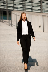 Fototapeta premium Young business woman walk on stairs leaving office building