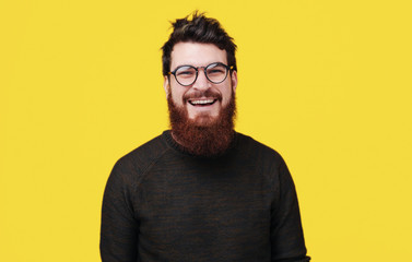 Handsome smiling bearded man standing over yellow background