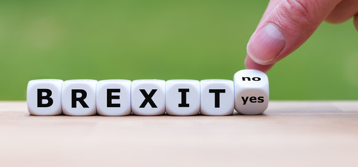 Hand turns a dice and changes the word "yes" to "no" symbolizing no Brexit
