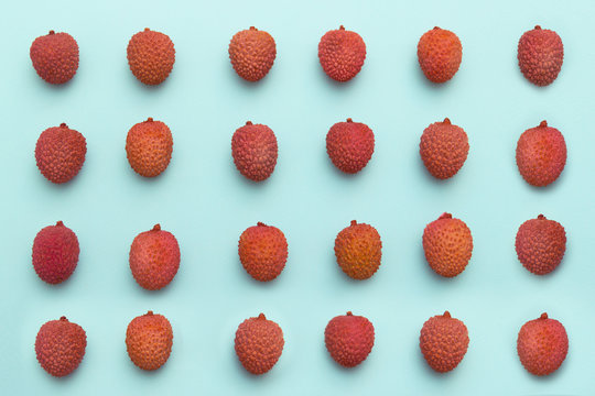 lychee fruits lie in rows on a turquoise blue background