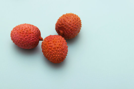 three lychee fruits lie on a turquoise blue background