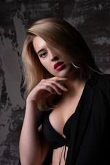 Closeup shot of sensual model with perfect skin wearing jacket and bra posing at studio with shadows