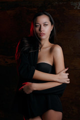 Studio portrait of young glamor girl wearing black lingerie, posing with red light