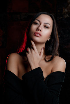 Studio portrait of young luxury model wearing lingerie and jacket, posing with red light