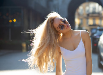 Amazing young model with long hair wearing glasses, posing at the passage in rays of sun. Copy space