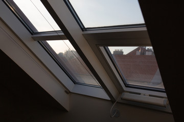 Modern mansard window in an attic room against city landscape