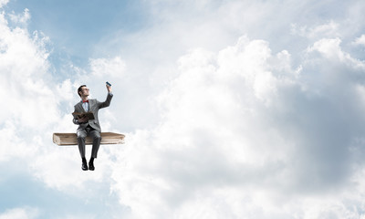 Young businessman or student floating in blue sky and studying the science
