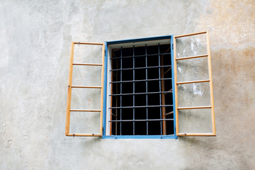 Old wooden window with bars outside the building. Empty space
