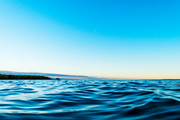 Water surface. View of a Sunset sky background. Dramatic gold sunset sky with evening sky clouds over the sea. View of a Crystal clear sea water texture. Landscape. Small waves. Water reflection