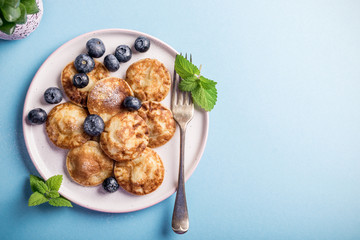 Dutch mini pancakes called poffertjes with blueberries, sprinkled with powdered sugar. Healthy food concept with copy space. Top view.