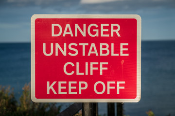 Sign: Danger unstable cliff, keep off, seen in Whitley Bay, Tyne And Wear, England, UK