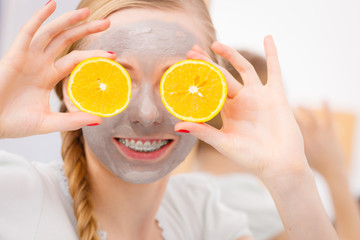 Happy young woman having face mask holding kiwi