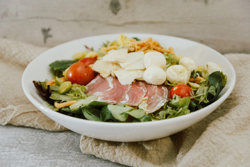 Salad with speck ham and egg, tomatoes