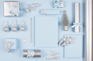 Modern soft minimalist christmas background - various blue and silver metallic gift boxes with shiny ribbons and bows, christmas tree, decorations on blue color backdrop, top view.