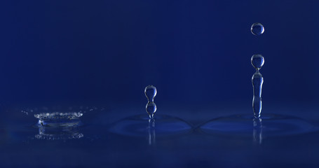 Choque y crecimiento de gota de agua sobre fondo azul