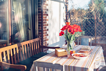 Rural life spring scene. April dinner near the house at sunset with tulips on the table