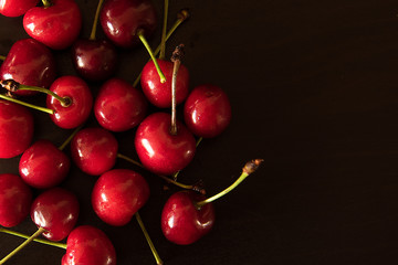 Top view of red ripe sweet cherries on black background