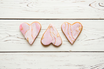 Obraz premium Three cookies in the shape of marble white hearts on wooden background