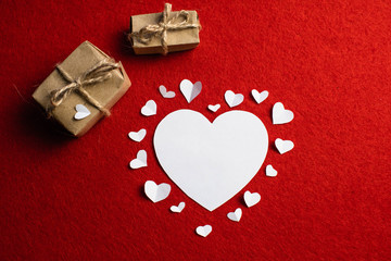 Love decoration of white paper hearts surrounded by big heart and two present boxes on red...