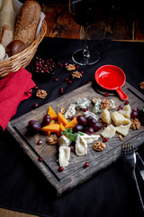 Fototapeta na wymiar Cheese plate served with grapes, honey and nuts on a wooden background. Various types of cheese