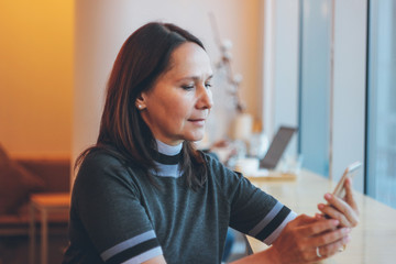 Beautiful middle-aged adult woman smiling and talking on the pho