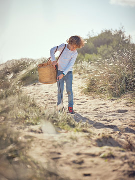 Boy with basket picking up garbage from ground