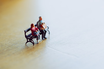 Miniature couple sitting together in warm light .